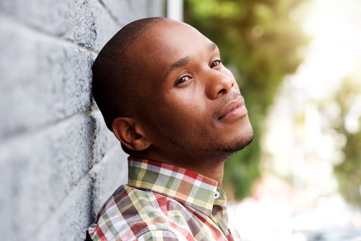 Young man leaning against wall and thinking