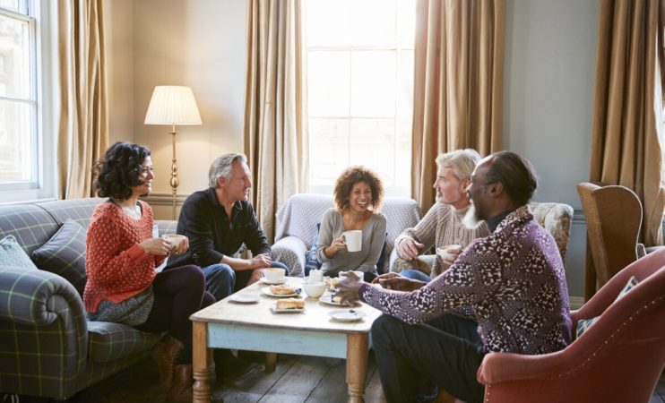 Group Of Middle Aged Friends Meeting Around Table In Coffee Shop