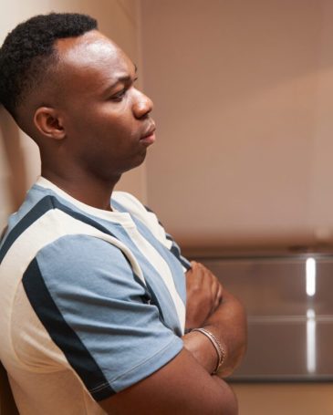 Multiracial person with folded arms near wall